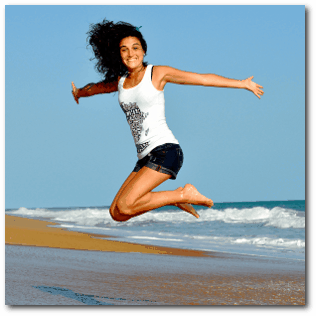 Junge Frau am Strand hüpft vor Freude in die Luft