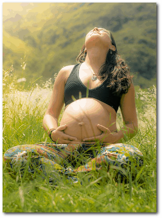 Massageklang - eine schwangere Frau sitzt im Gras und geniesst die Sonne und ihr Baby