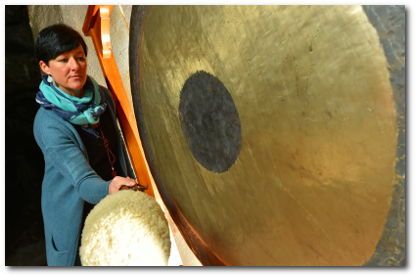 Katrin Leutbecher (Massageklang) schlägt mit der rechten Hand den großen Gong - sie steht zum Klangkonzert in der Marienglas-Höhle
